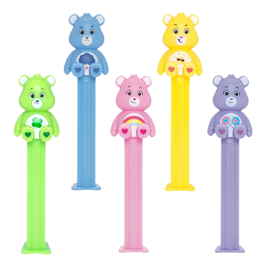 Five PEZ Care Bears dispensers lined up together — green Good Luck Bear with a four-leaf clover badge, blue Grumpy Bear with a rain cloud badge, pink Cheer Bear with a rainbow badge, yellow Funshine Bear with a sun-and-sunglasses badge, and purple Share Bear with a heart-lollipop badge.