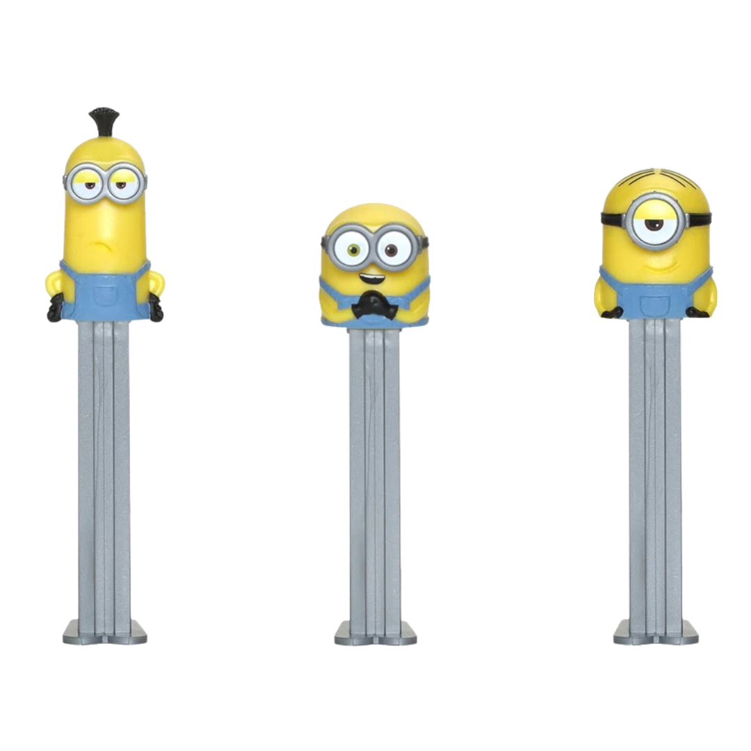 Three PEZ Despicable Me dispensers lined up together — Stuart with a spiky hair tuft, Kevin with a tall banana-shaped head, and Bob with mismatched eyes, all in blue overalls on gray candy stems.