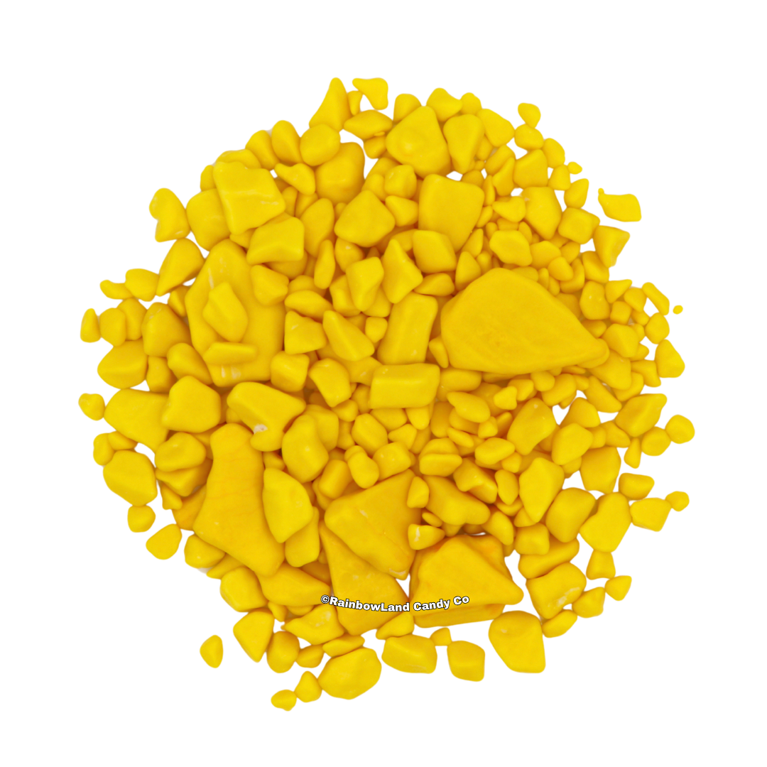A pile of yellow, gold nugget-shaped banana bubble gum pieces in various sizes, scattered against a white background.