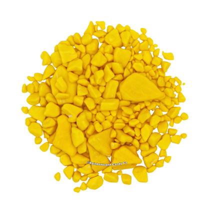 A pile of yellow, gold nugget-shaped banana bubble gum pieces in various sizes, scattered against a white background.