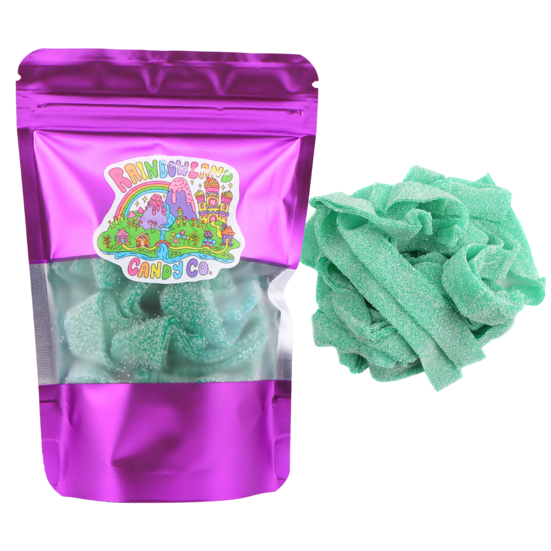 RainbowLand Candy Co. Green Apple Sour Belts in a purple metallic resealable stand-up pouch with a clear window, shown beside a loose pile of bright teal-green, sugar-coated green apple sour candy belts.