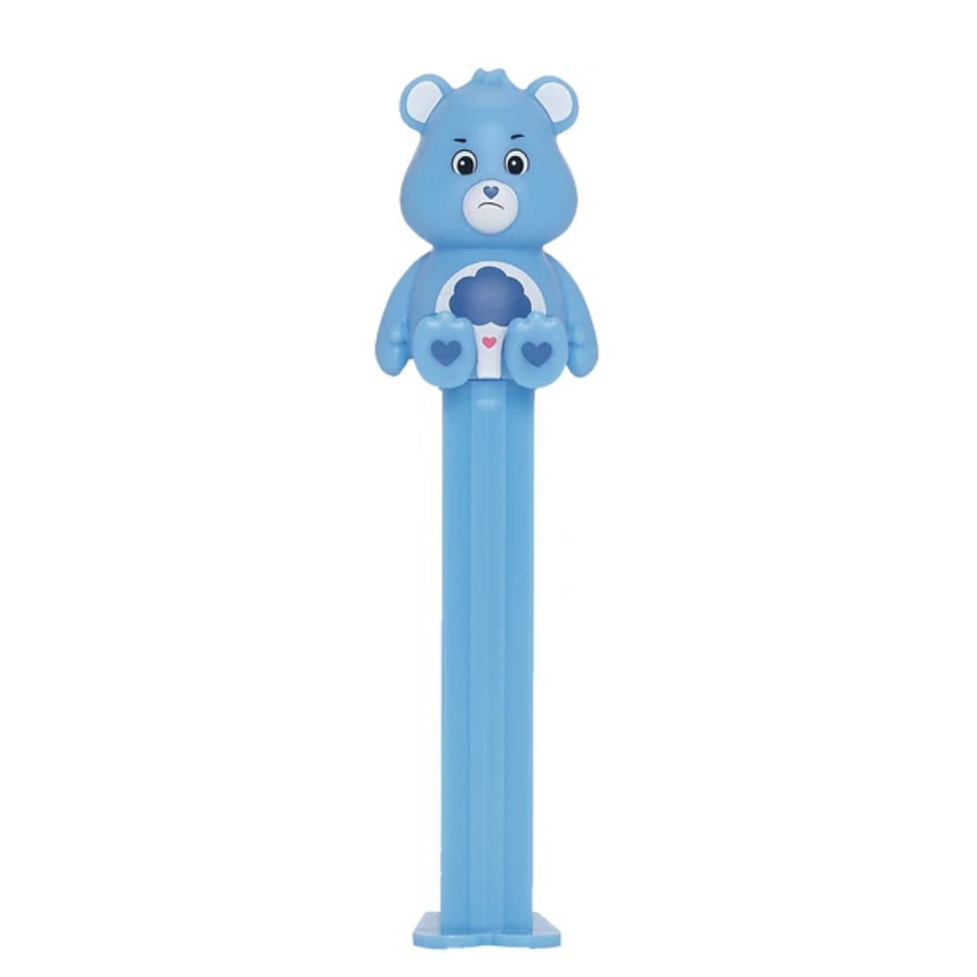 Blue Grumpy Bear PEZ dispenser with a rain cloud belly badge, furrowed brow, heart-shaped nose, and blue candy stem.