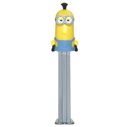 A Minions-themed Pez dispenser featuring a yellow character with blue overalls and a black mohawk, mounted on a long silver metal handle, set against a plain white background.